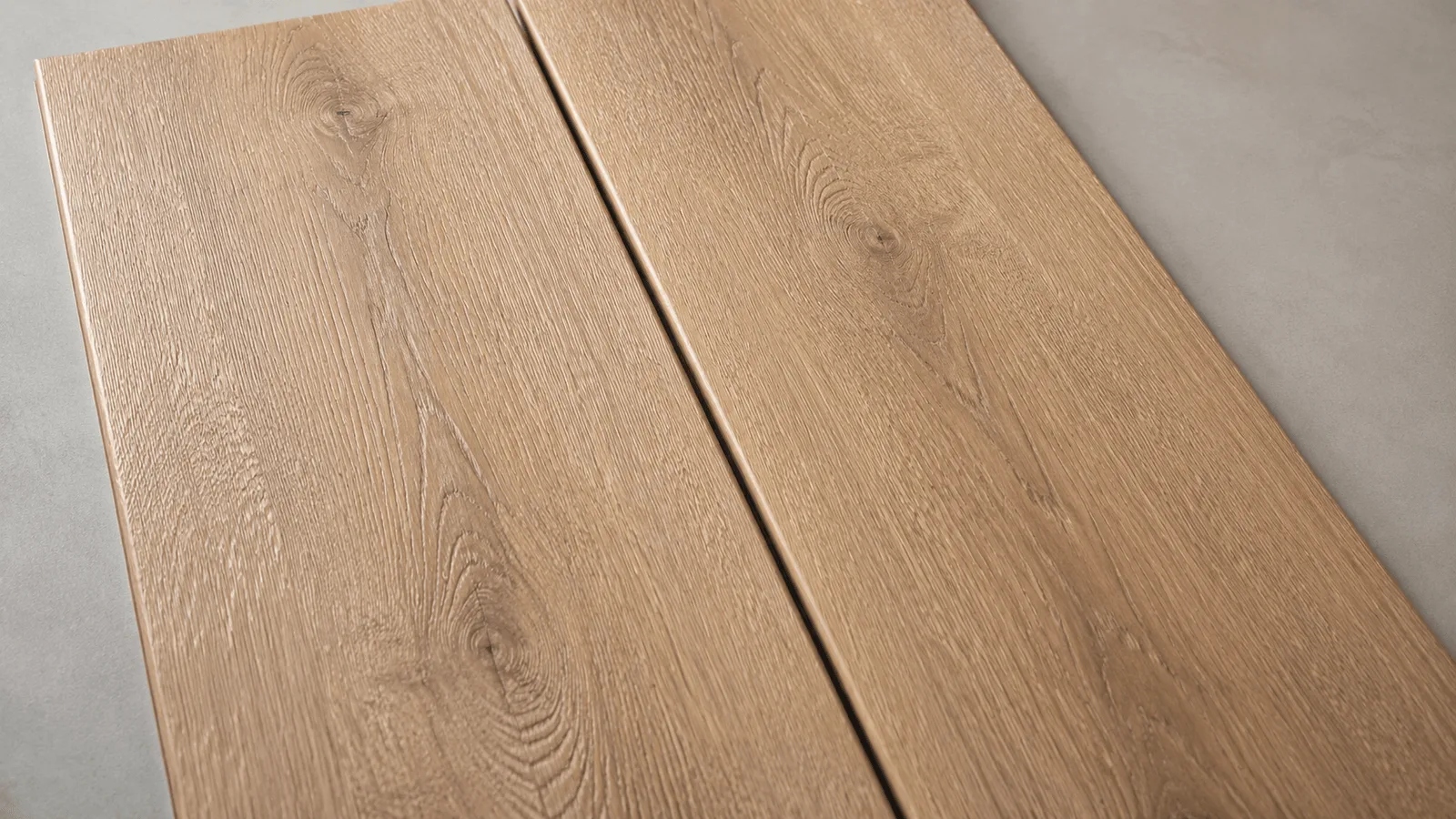 A luxury vinyl plank and a laminate plank laid side by side, showing how similar the two look from above