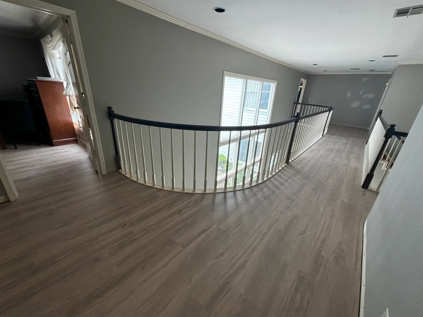 Gray luxury vinyl plank on a curved upstairs landing with an iron railing in a Tulsa metro home