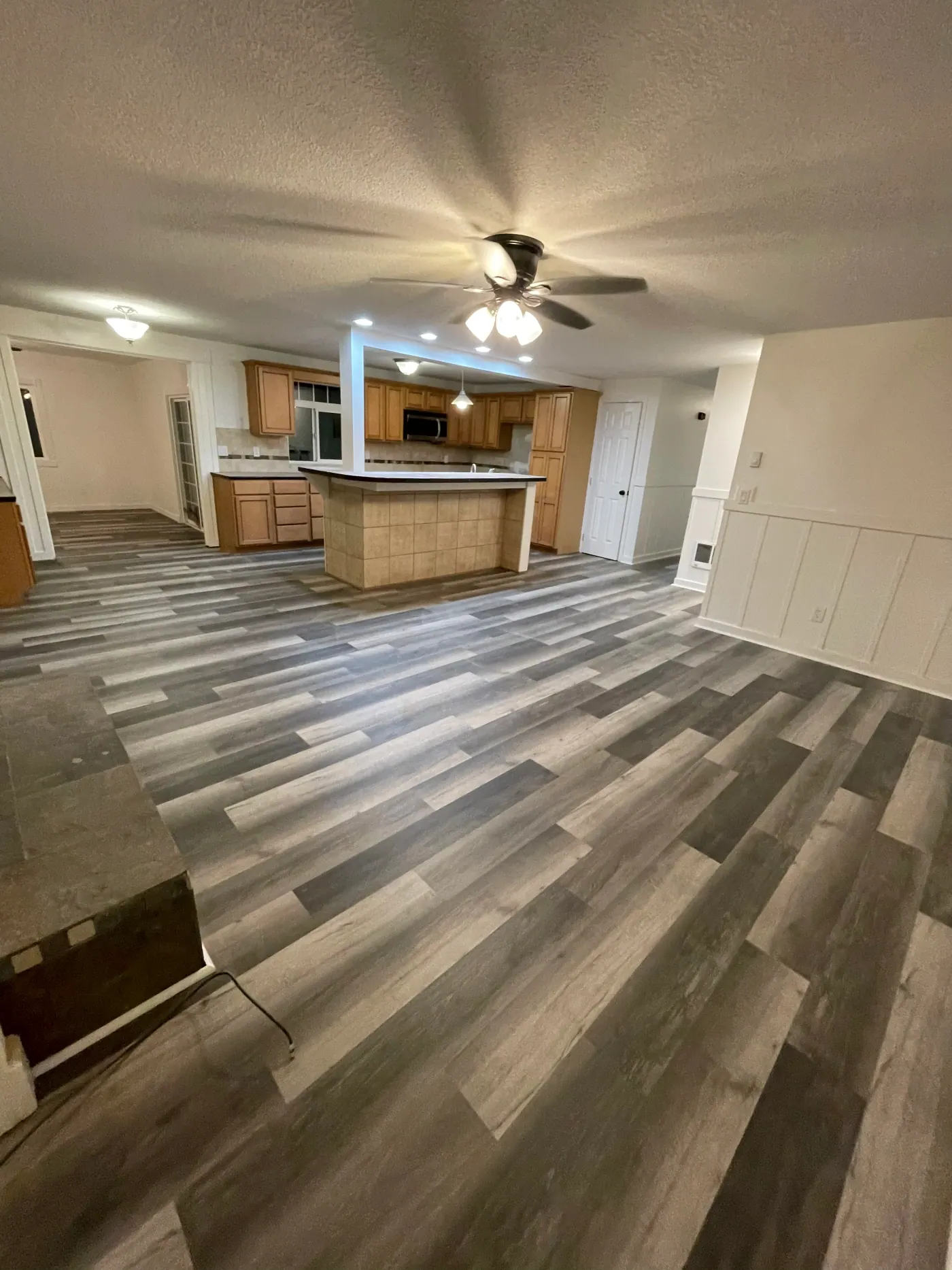 Gray luxury vinyl plank flooring through an open living and kitchen area in Tulsa, OK