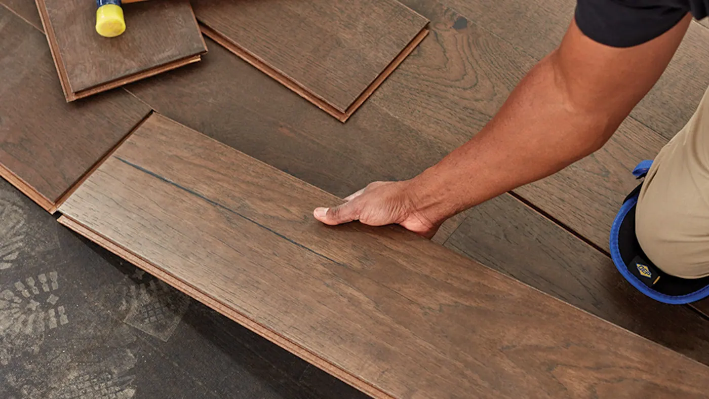 Installer setting a hardwood plank during a wood floor installation in Tulsa, OK