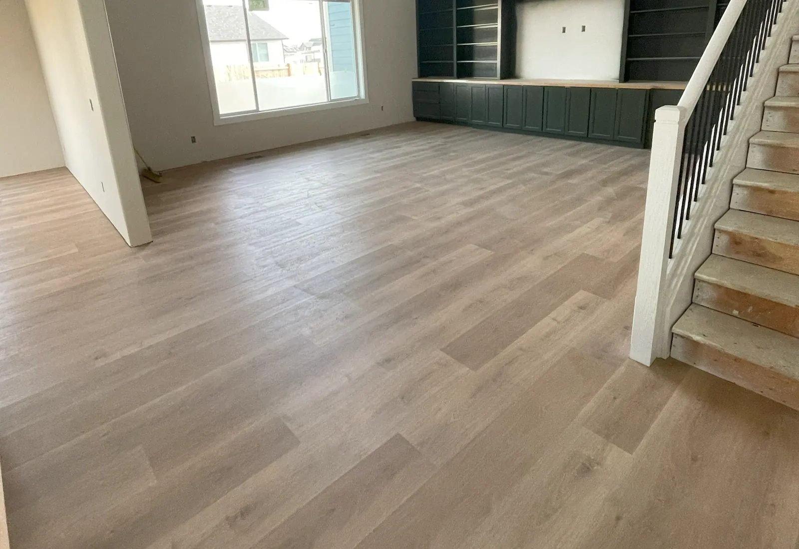 Laminate flooring running through an open plan room with a staircase in a Tulsa, OK home