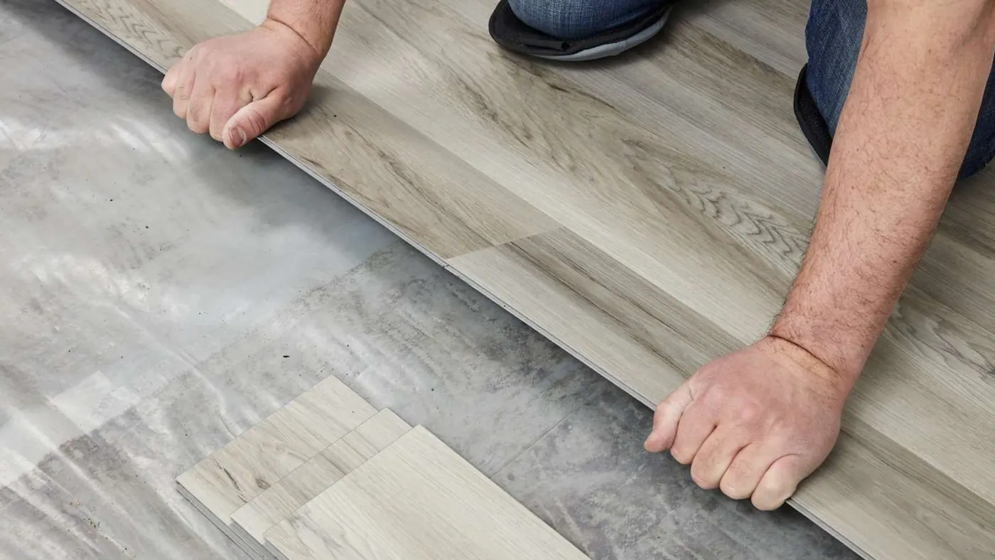 Installer setting a luxury vinyl plank tight against the previous row during a flooring installation in Tulsa, OK