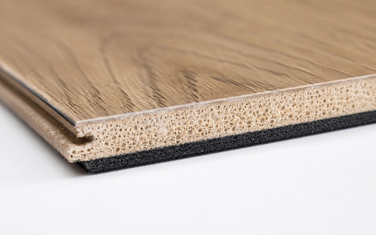 Close up of a WPC luxury vinyl plank edge showing its softer wood polymer core and attached pad
