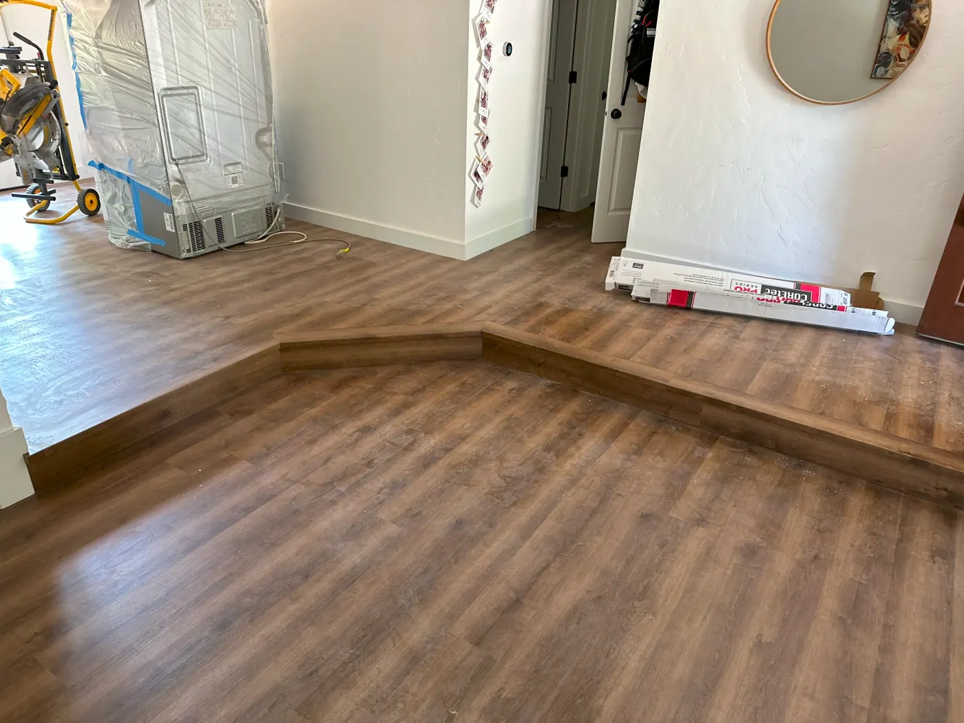 Plank flooring in a living room with a fireplace and wall mirror in a Tulsa, OK home