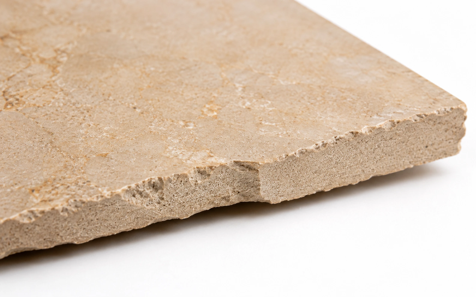Close up of a porcelain floor tile edge showing a dense, fine grained clay body running the full thickness with no colour change at the surface
