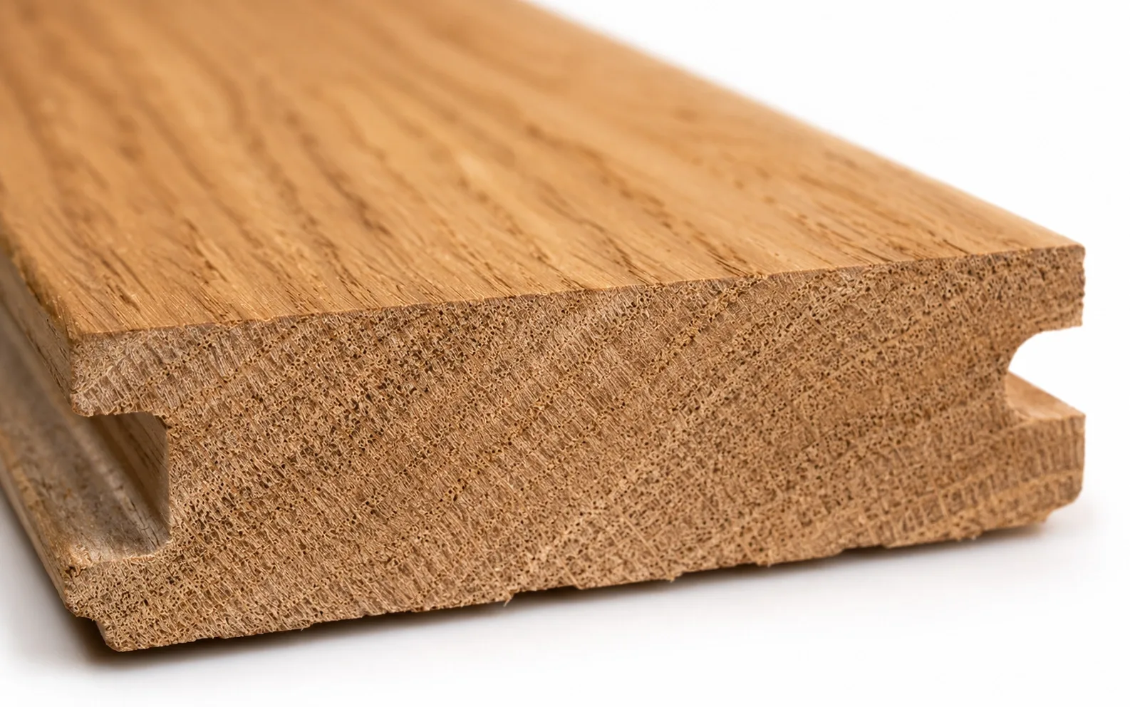Close up of a solid oak hardwood flooring plank edge showing one continuous piece of wood through the full thickness with a machined tongue