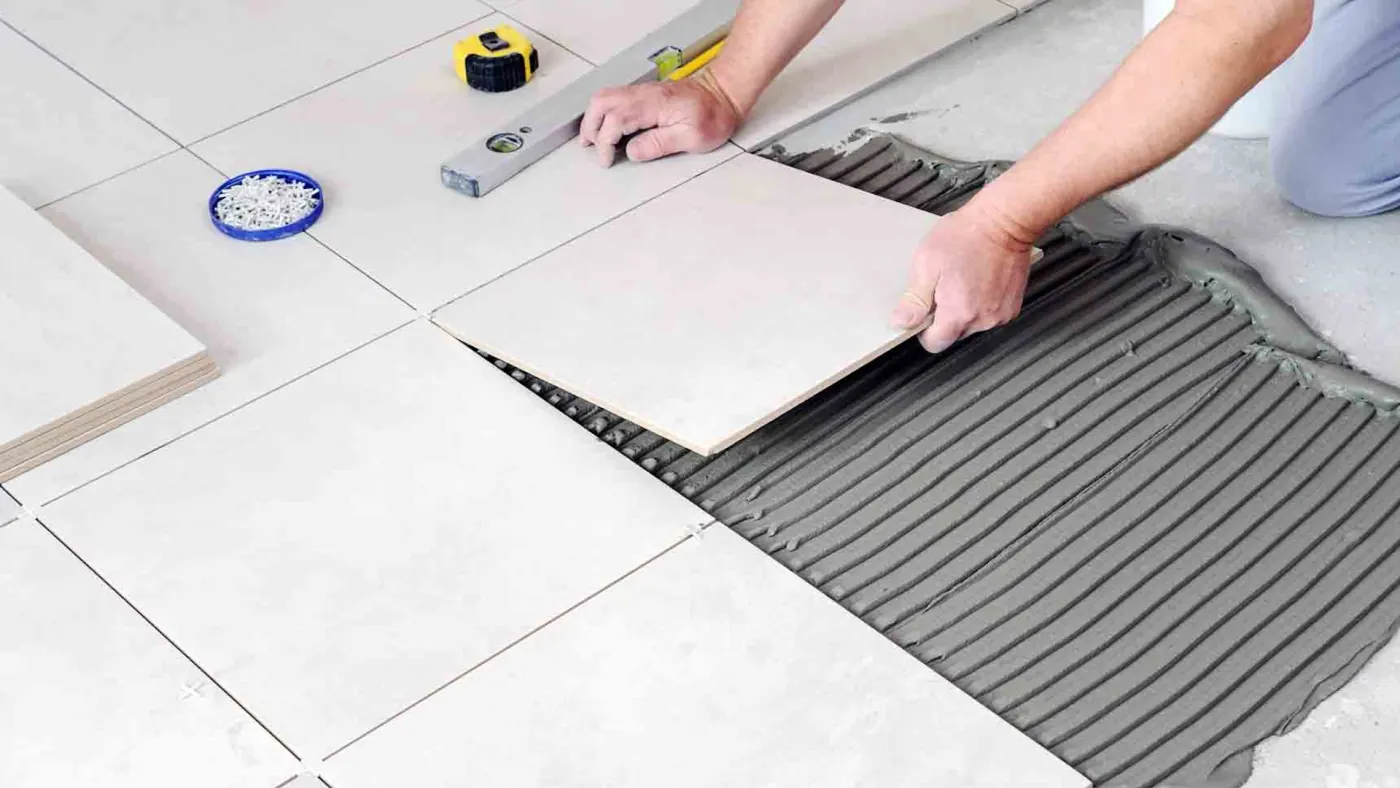 Installer setting a floor tile into full mortar coverage during a tile installation in Tulsa, OK