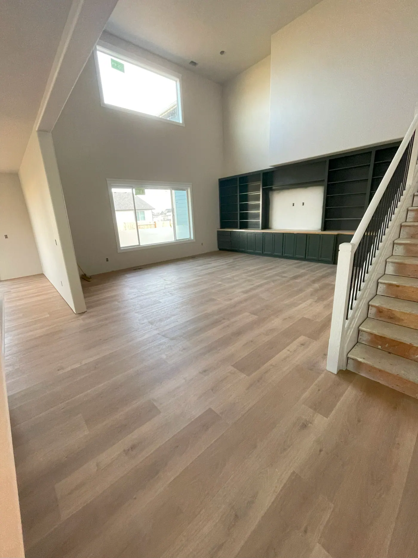 Plank flooring in a two story living room with built in shelving in a Tulsa metro home