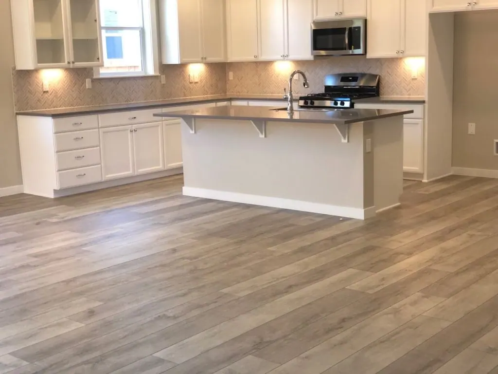 Warm wood flooring in a white kitchen with a center island in a Tulsa, OK home